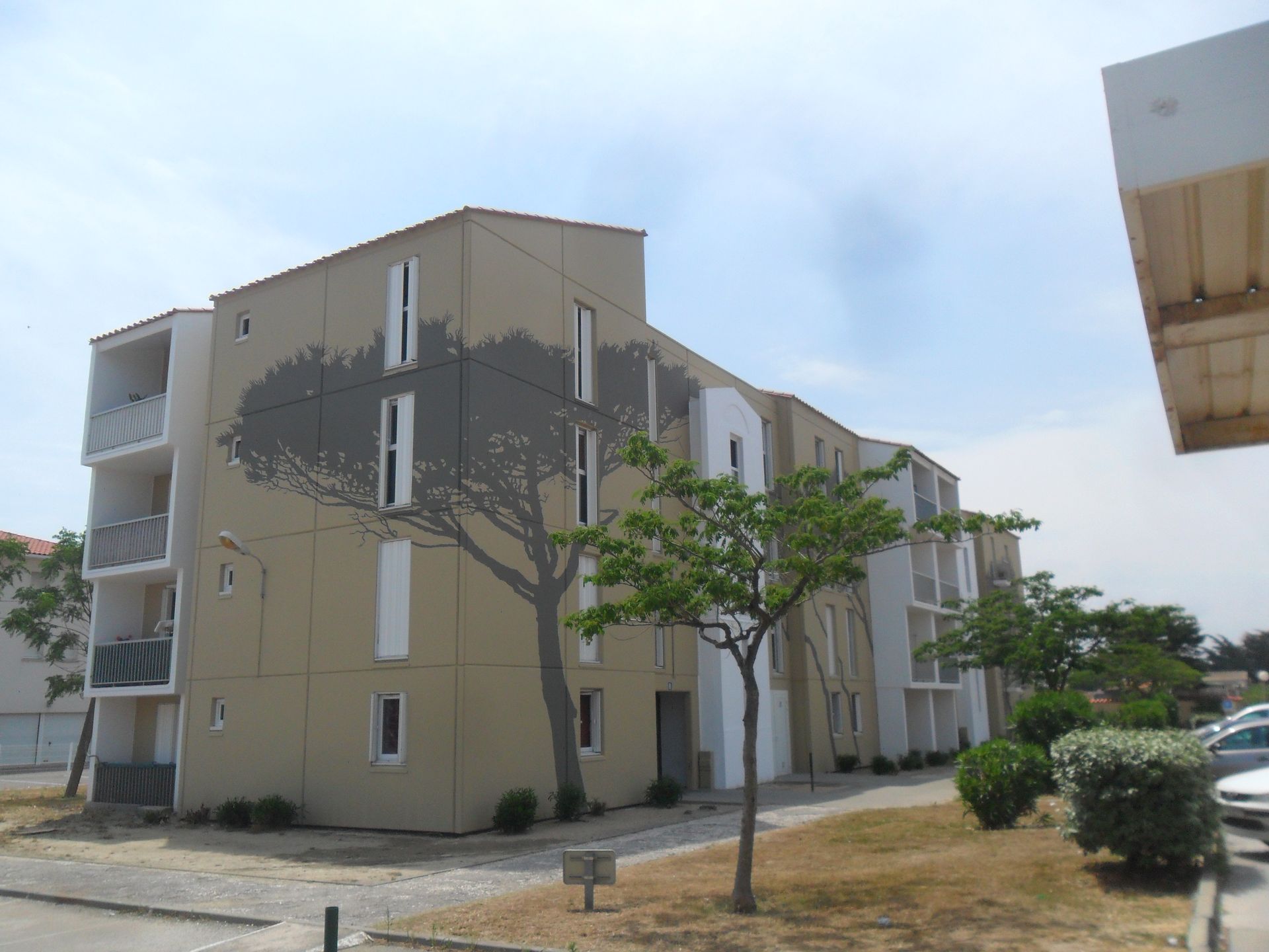 Un immeuble d'appartements beige à plusieurs étages, orné d'une grande fresque murale 