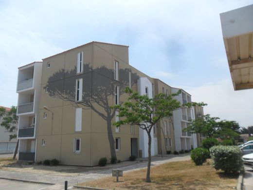 Un immeuble d'appartements beige à plusieurs étages, orné d'une grande fresque murale 