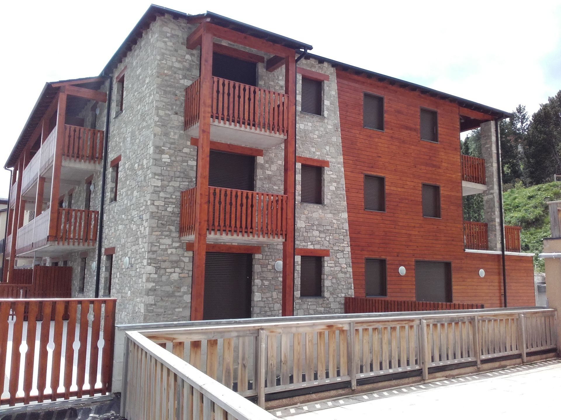 Un immeuble à plusieurs étages présentant une façade en pierre avec des balcons en bois