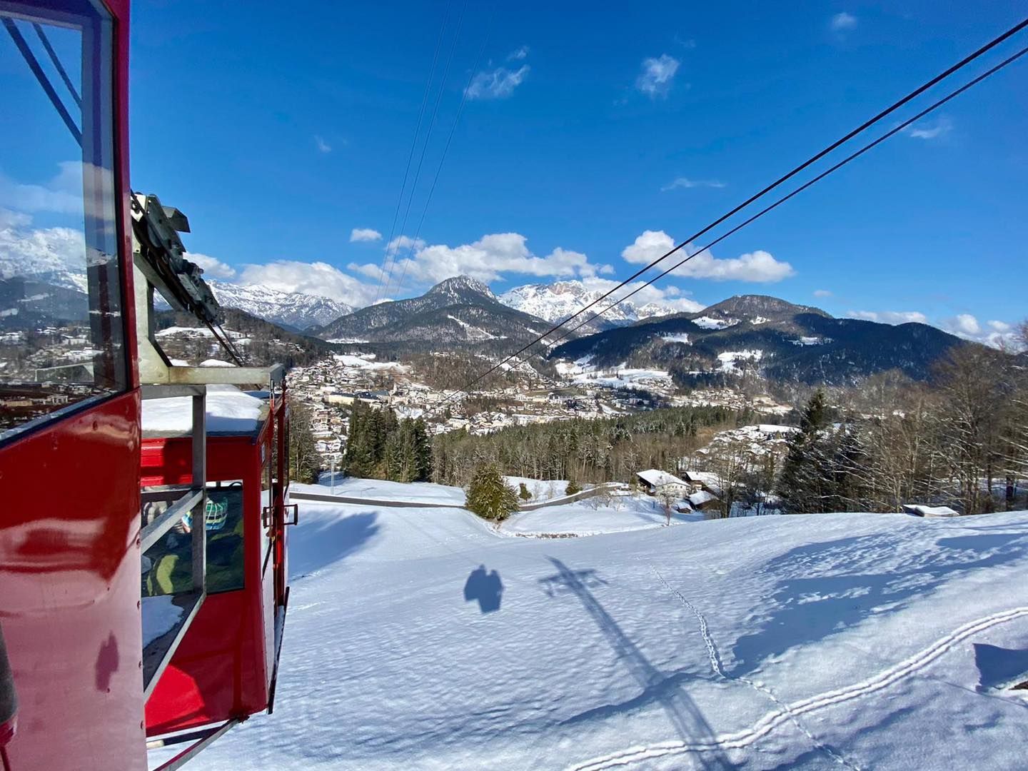 Verschneite Bergskipiste mit rotem Sessellift und blauem Himmel
