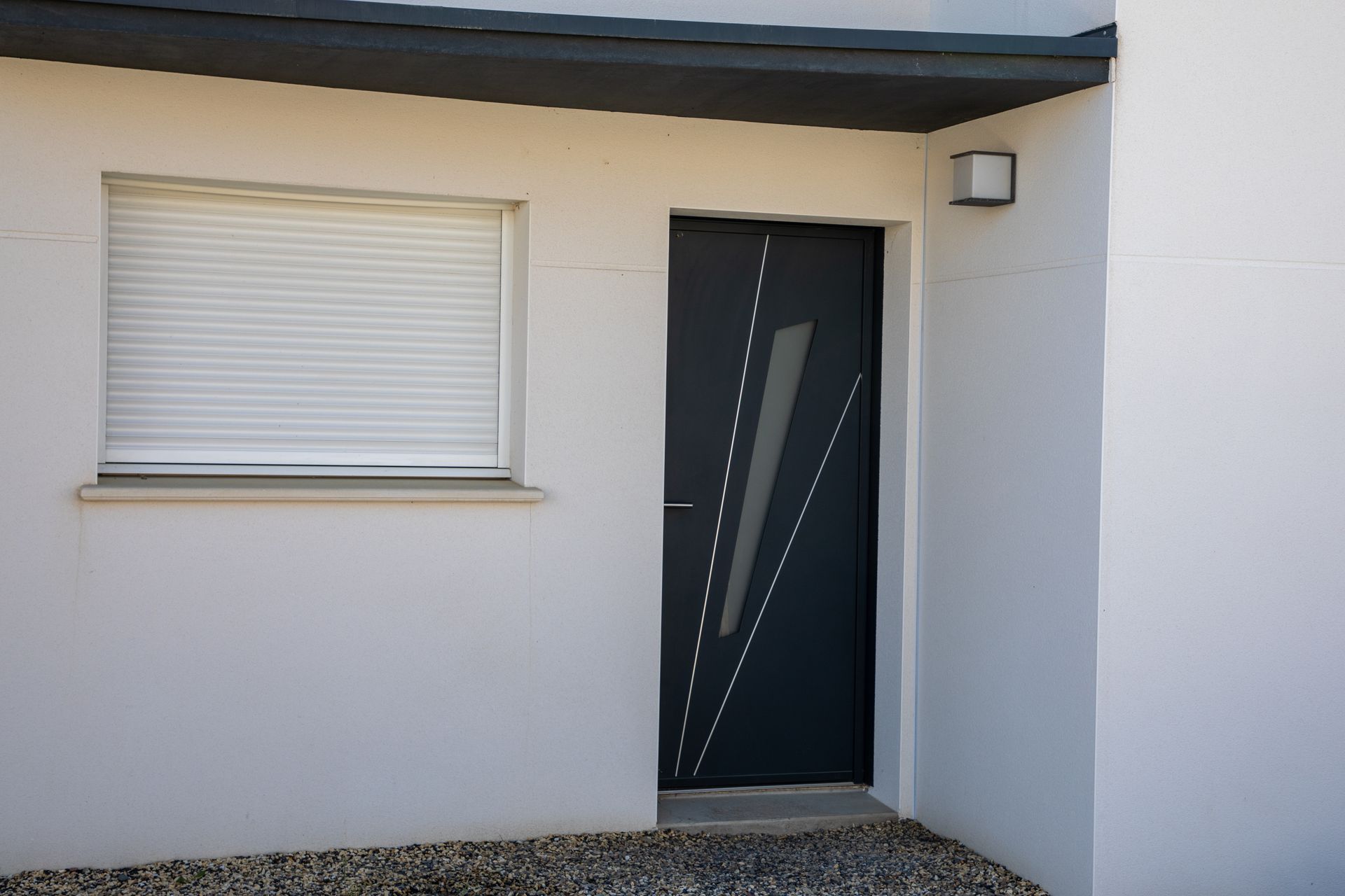 Porte d'entrée en aluminium de couleur noir d'une maison aux volets fermés