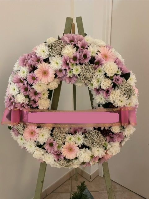 Couronne de fleurs roses et blanches sur portant avec bandeau rose