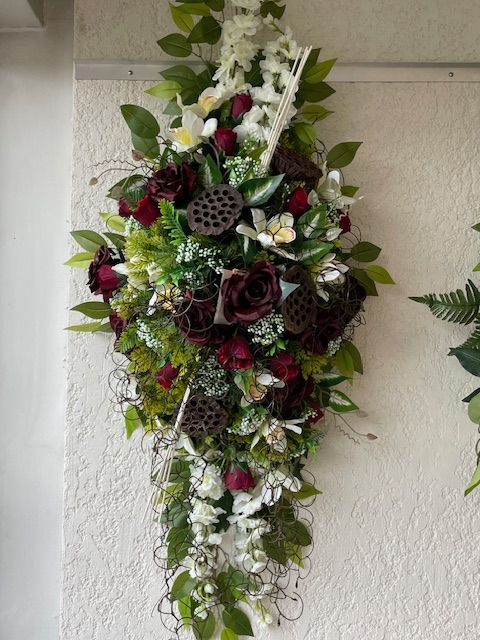 Coussin de fleurs long avec roses bordeaux accroché au mur