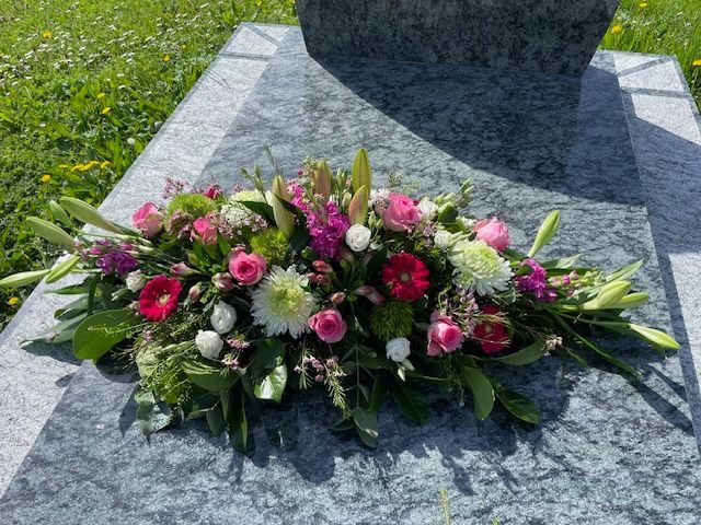 Coussin de fleurs roses et blanches sur pierre tombale