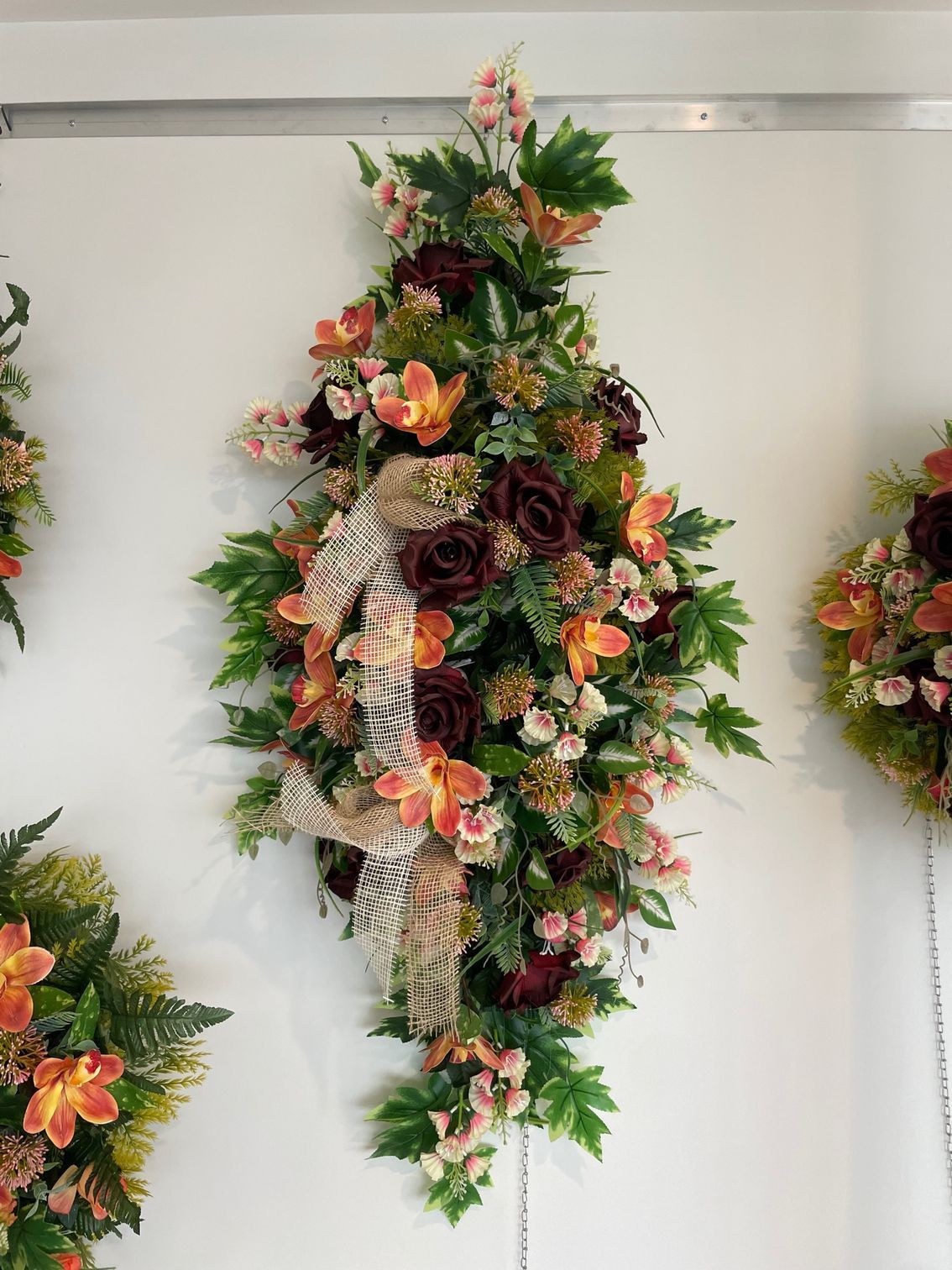Coussin de fleurs orange et bordeaux accroché au mur