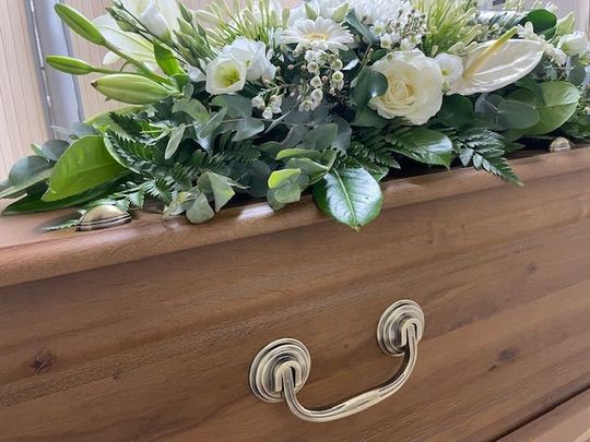 Gerbe de fleurs blanches sur cercueil en bois