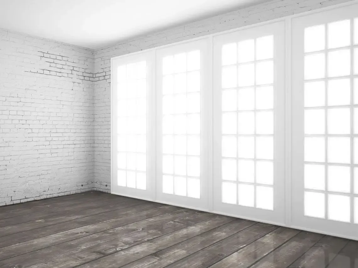 Una habitación vacía con suelo de madera y paredes de ladrillo blanco.