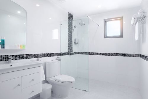 Un baño con inodoro, lavabo, espejo y ducha.