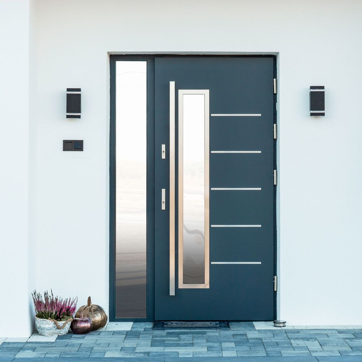 Porte d'entrée bleue moderne avec panneau en verre dépoli, poignée argentée et plantes en pot à côté d'un mur blanc.