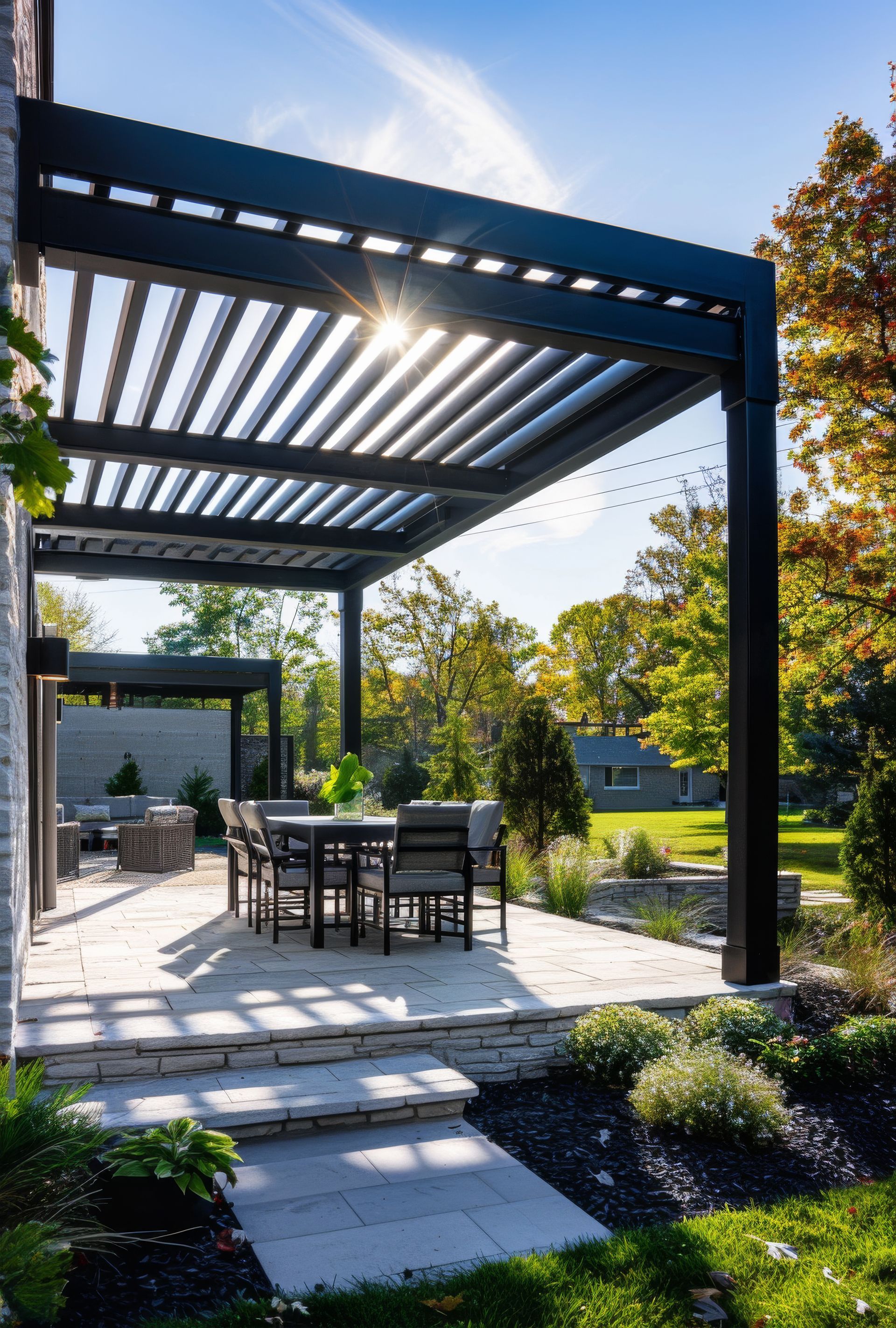 Terrasse moderne dans un jardin ensoleillé, avec pergola noire, table à manger et pas japonais.