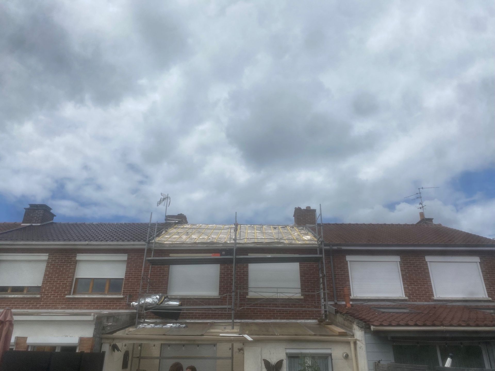 Toit en tuiles d'argile orange contre un ciel bleu vif avec des nuages ​​blancs.