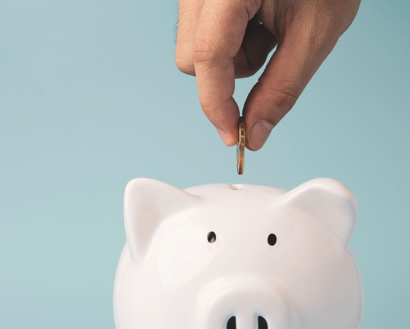 Une tirelire et une main qui met une pièce dedans