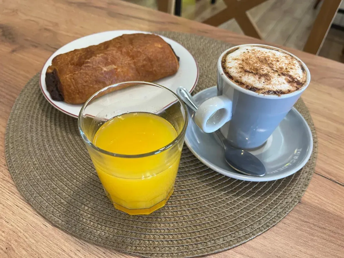 Un plato de pescado a la parrilla, rodajas de patata sazonadas y una pequeña guarnición de ensalada de col.