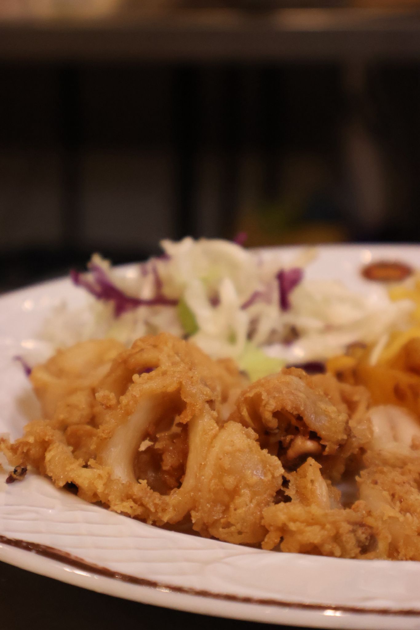 Plato de calamares fritos con repollo rallado en la mesa de un restaurante.