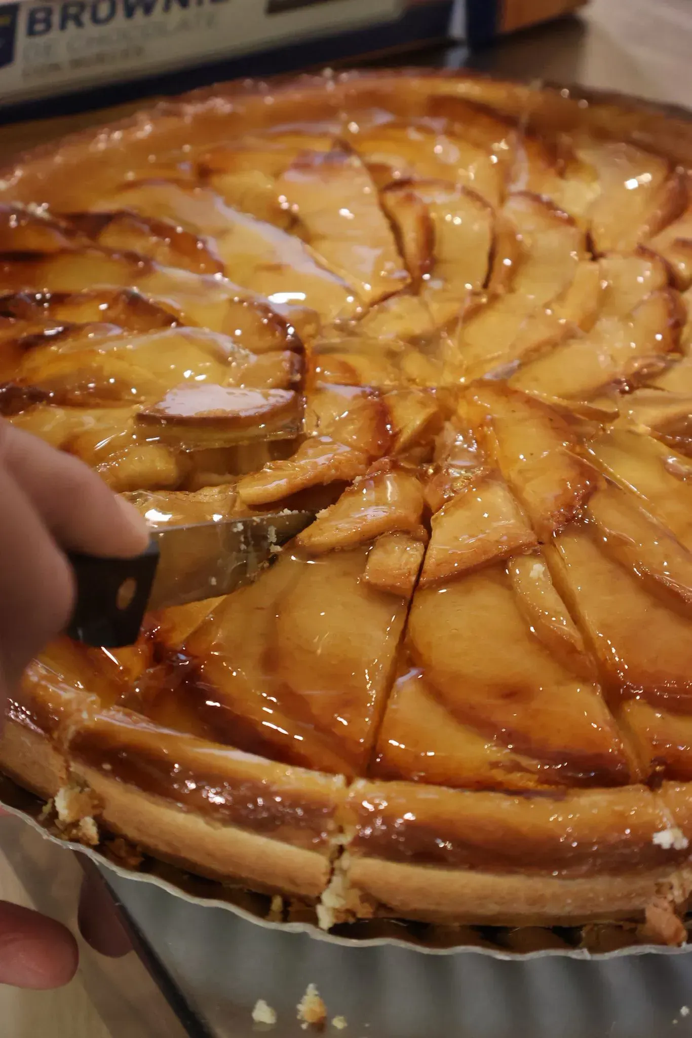 Cortar a mano una tarta de manzana brillante sobre una bandeja.