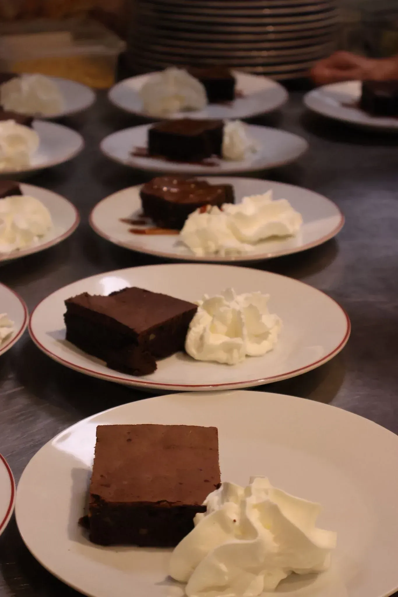Varios platos alineados sobre un mostrador de metal, cada uno con un brownie .