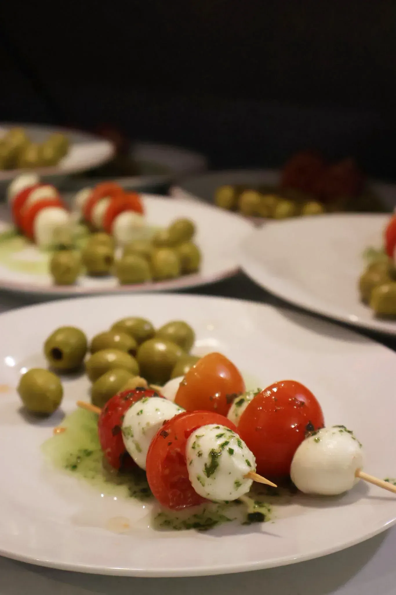 Brochetas de aperitivo con tomates cherry y bolitas de mozzarella, adornadas con hierbas y servidas.