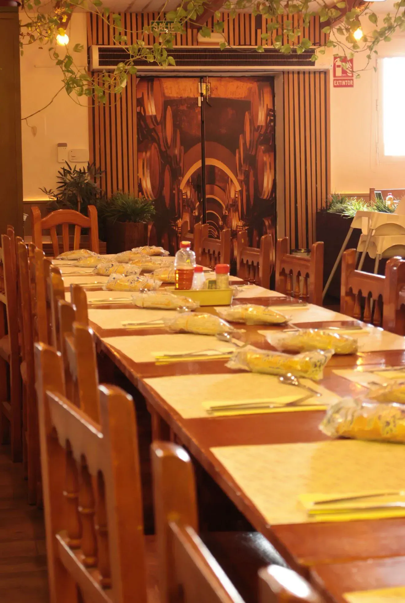 Una larga mesa de comedor de madera preparada para una comida en un restaurante rústico.