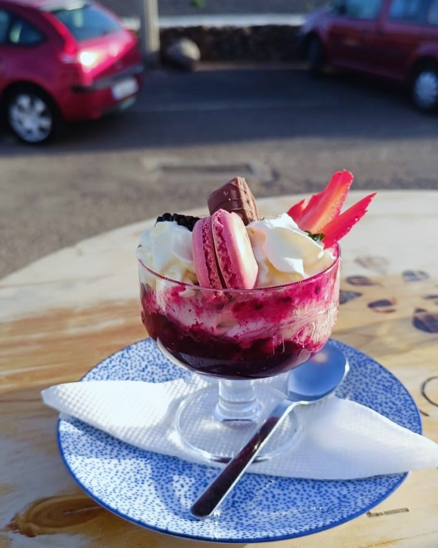 Un tazón de helado con macarons y fresas encima.