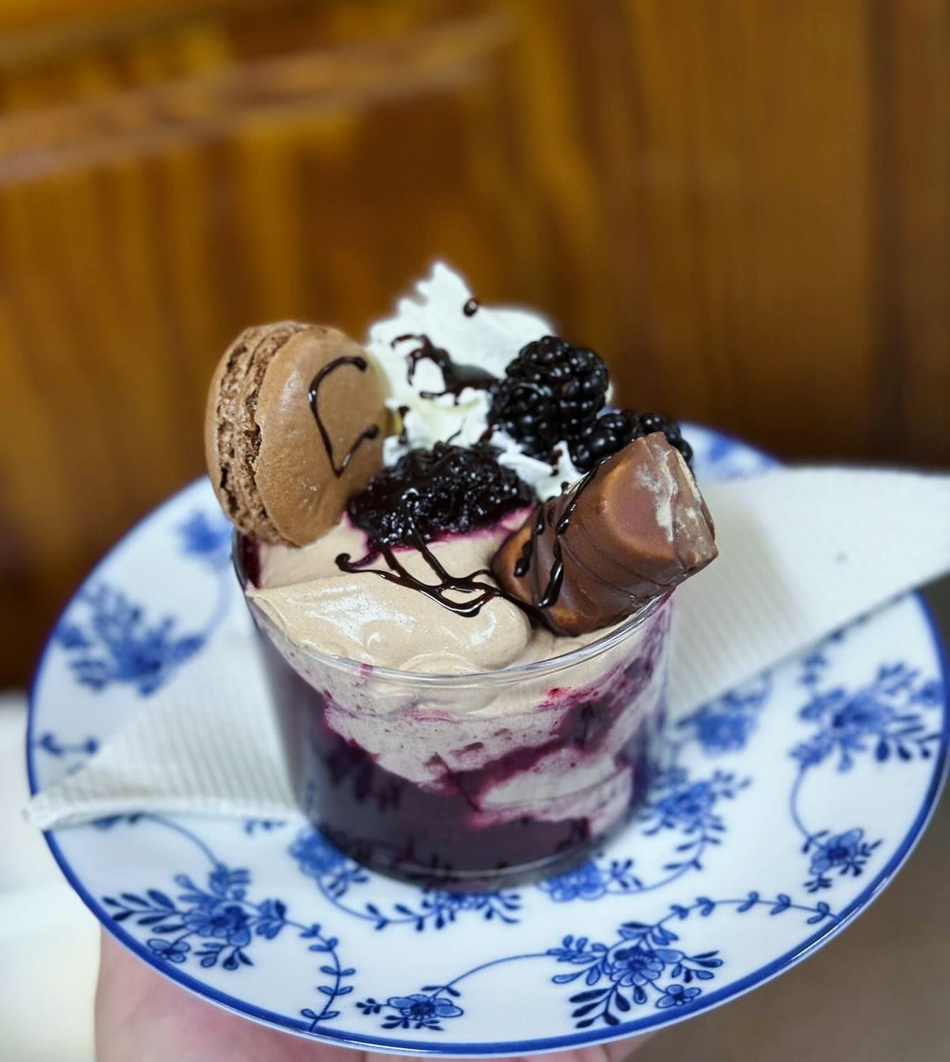 Una persona sostiene un plato azul y blanco con un postre encima.