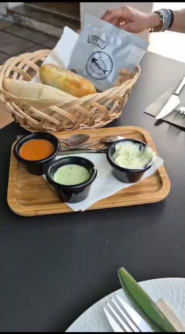 Una canasta de comida está en una bandeja de madera sobre una mesa.