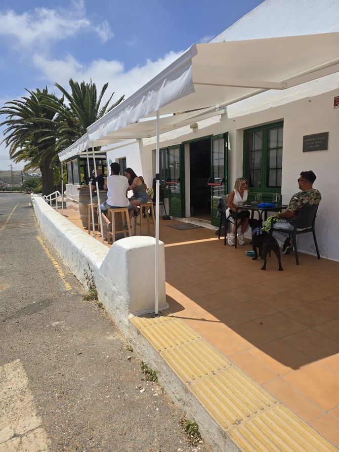 Un grupo de personas están sentadas en mesas afuera de un edificio.