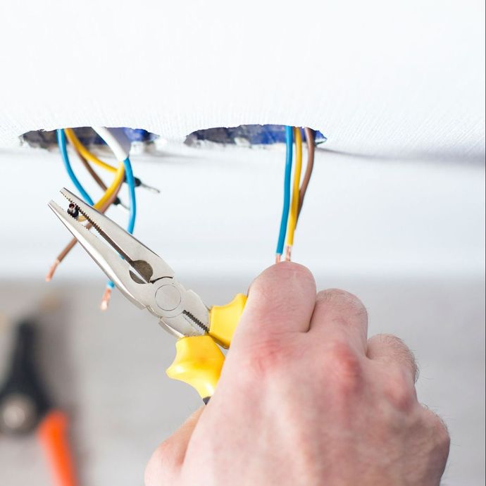 Un technicien coupe un fil qui sort d'un mur