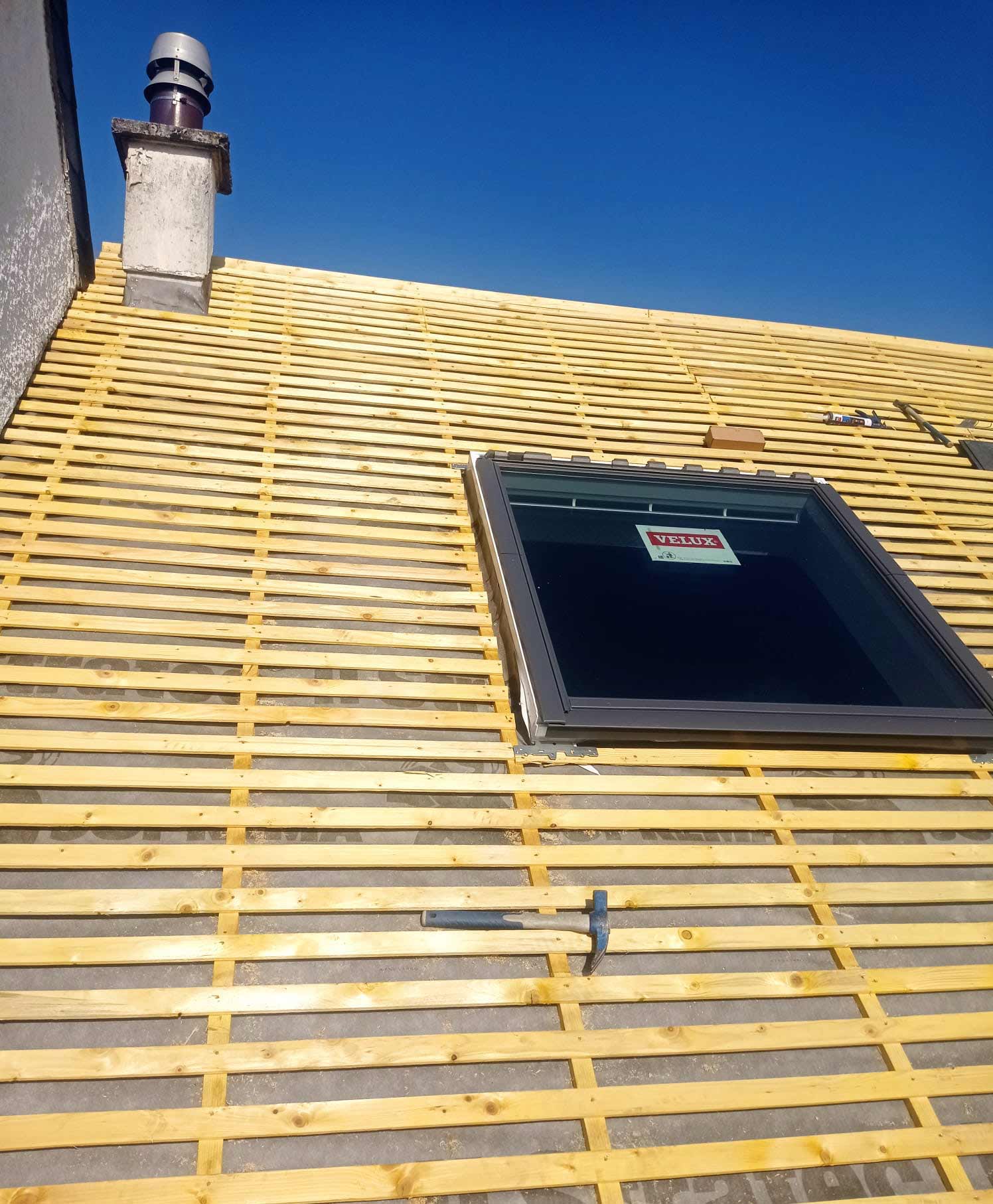 Toiture avec un Velux en cours de recouvrement