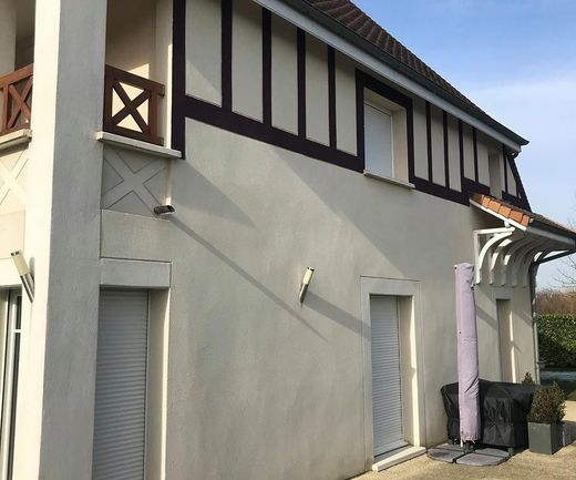 Extérieur d’une maison crépie avec des boiseries foncées, des fenêtres à volets et une petite allée