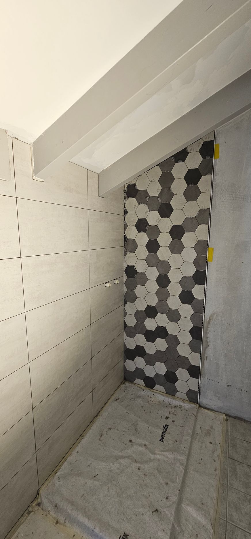 Vue intérieure d'une pièce avec un mur blanc et une armoire marron. Une fenêtre avec des stores se trouve à gauche.