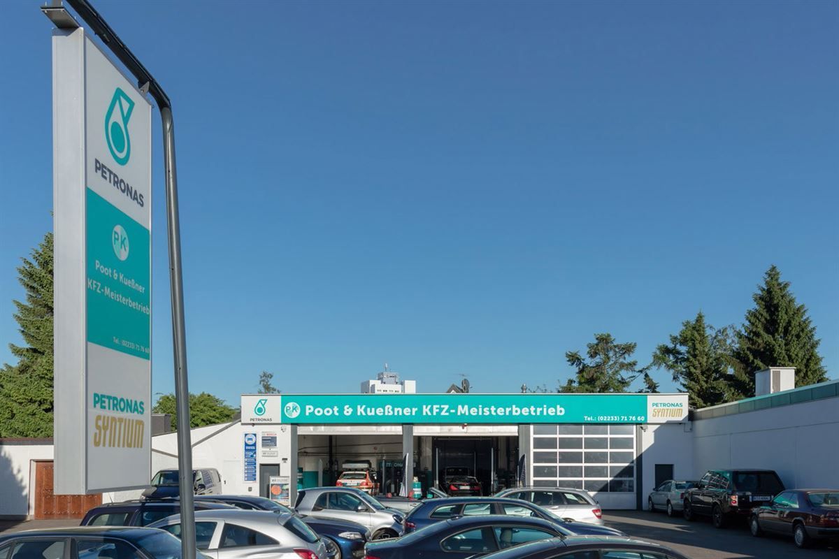 Viele Autos parken vor einem Petronas-Schild