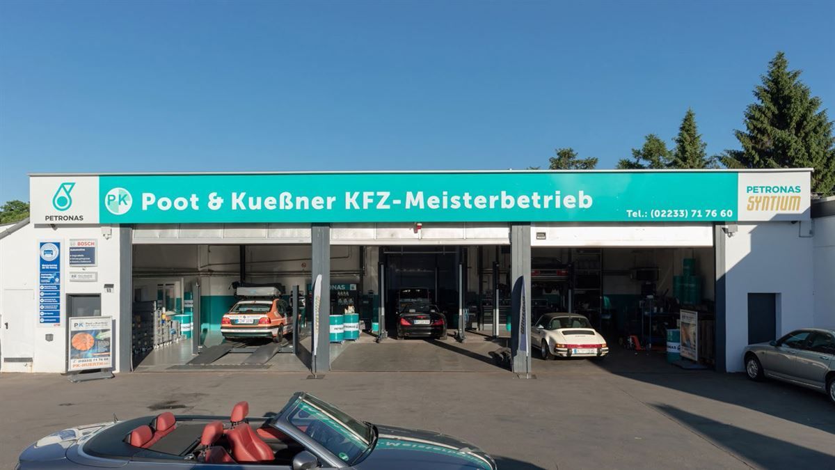 A car is parked in front of a poot & kuebner kfz-meisterbetrieb
