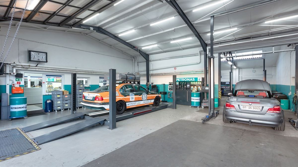 Ein Auto steht mit anderen Autos auf einer Hebebühne in einer Garage