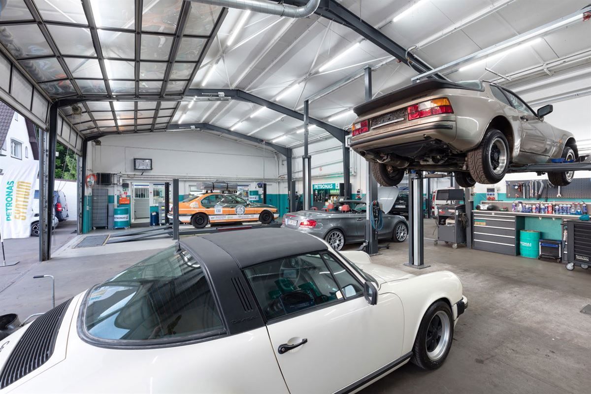 Zwei Autos stehen auf einer Hebebühne in einer Garage