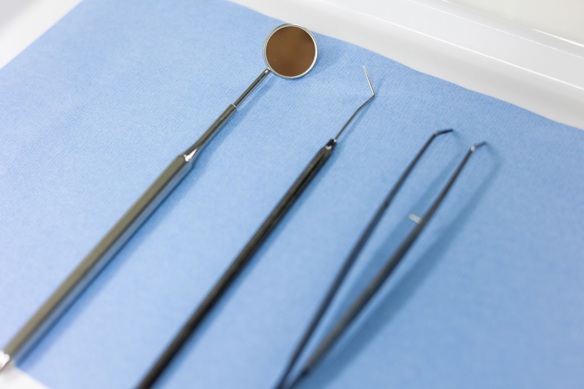 Zahnspiegel, Sonde und Pinzette auf einem blauen sterilen Tuch.