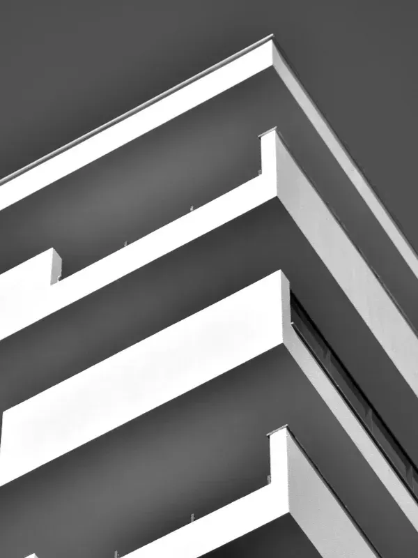 Patrón geométrico abstracto en blanco, negro y gris con líneas angulares superpuestas y esquinas afiladas.