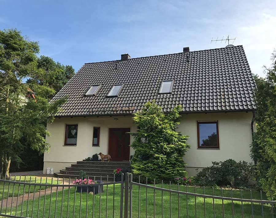 Ein weißes Haus mit schwarzem Dach und einem Zaun davor