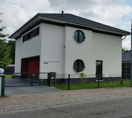 Ein weißes Haus mit schwarzem Dach und runden Fenstern