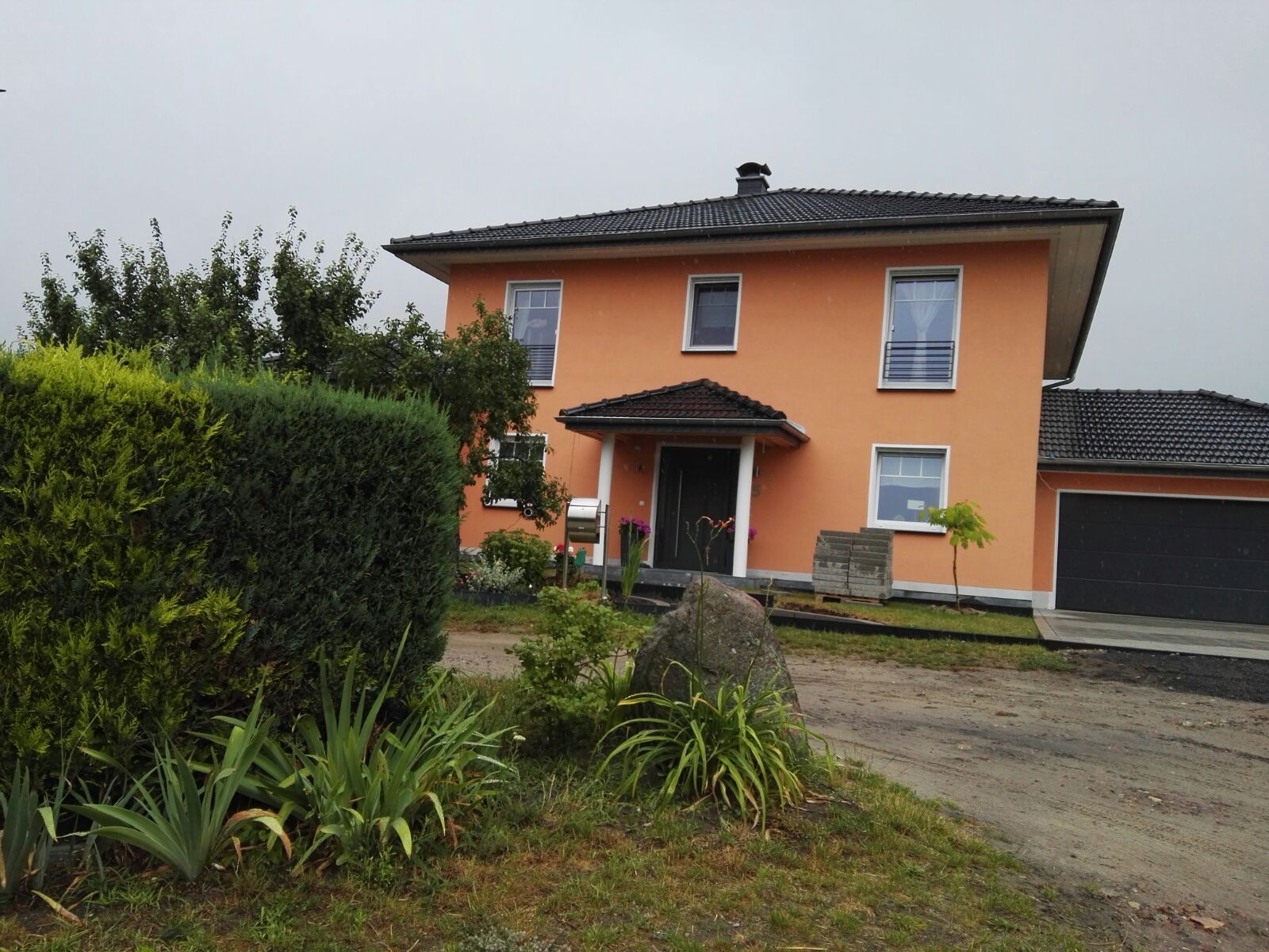 Ein großes orangefarbenes Haus mit einem schwarzen Garagentor