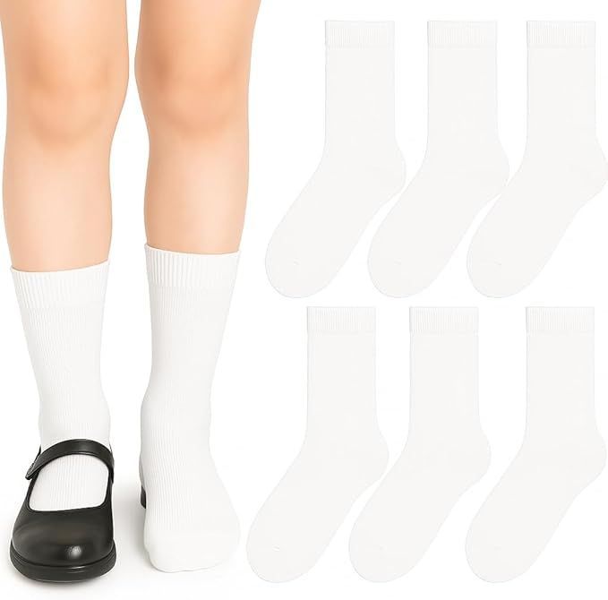 Piernas de un niño con calcetines blancos y zapatos escolares negros, con una pila de más calcetines blancos.