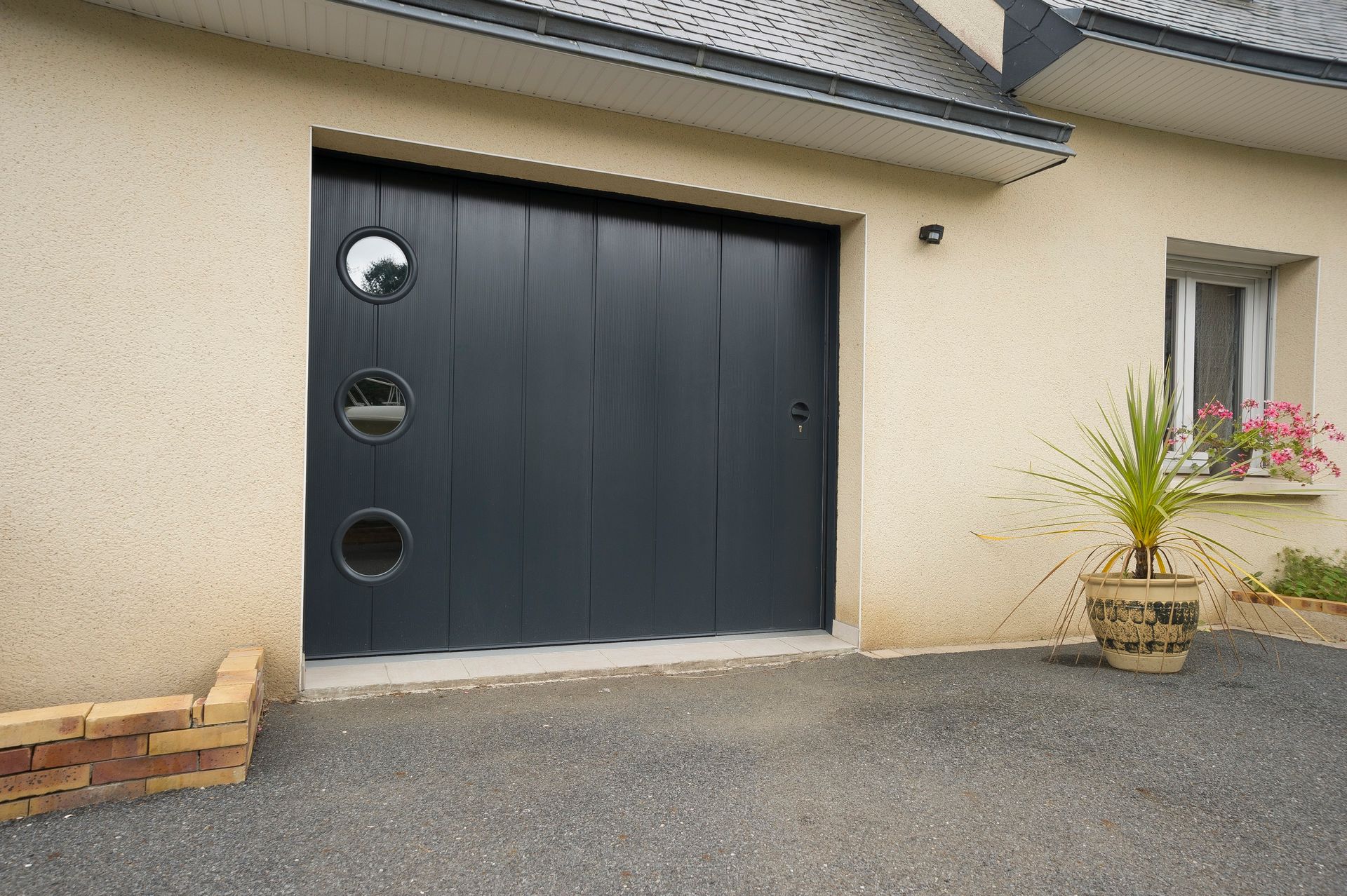 Porte de garage noire et petites fenêtres en cercle