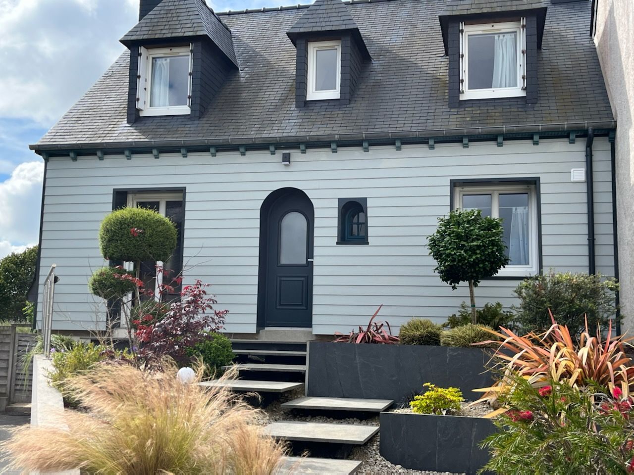 Face avant d'une habitation avec jardin et bardage