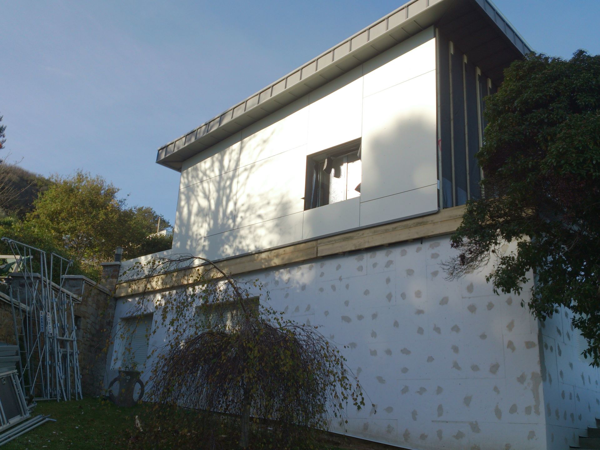 Vue en contre plongée sur la rénovation d'un domicile avec arbuste sur le côté