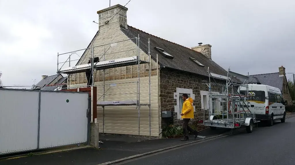 Installation de bardage sur une maison avec mur en pierre