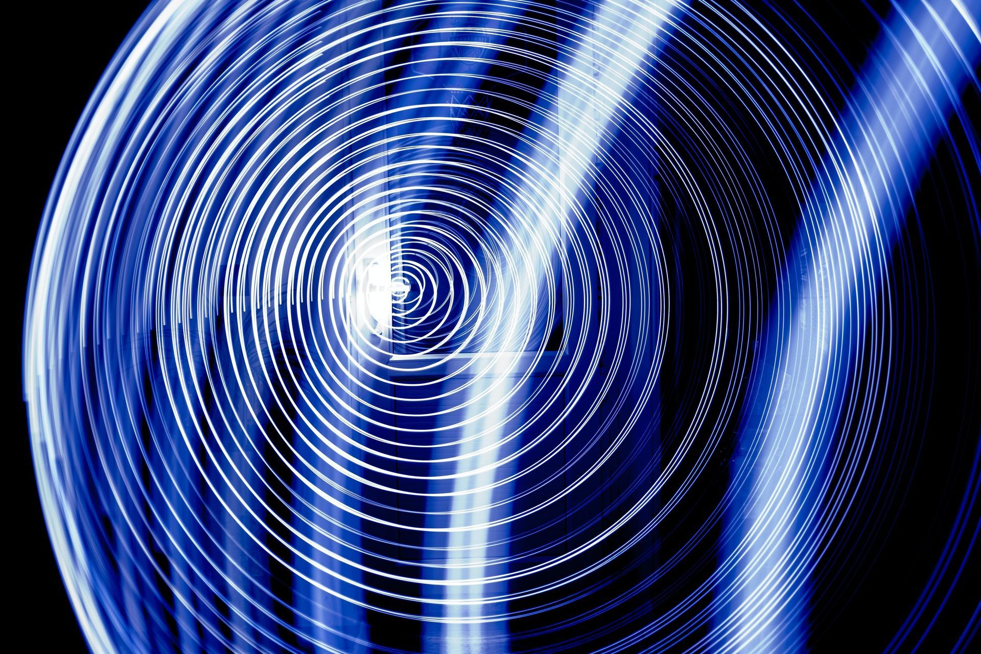 Círculos concéntricos azules y blancos con rayas diagonales sobre un fondo negro.