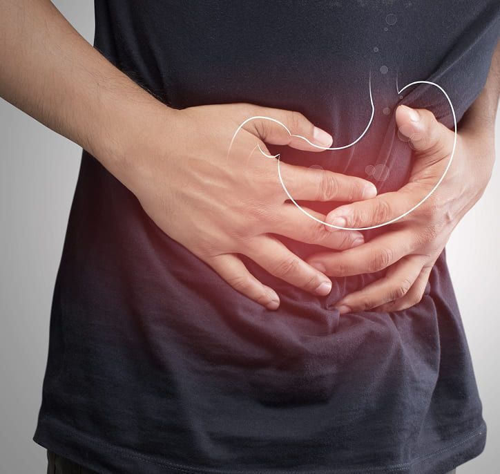 Persona que se agarra el estómago con dolor; un brillo rojo resalta el abdomen y se delinea el estómago.