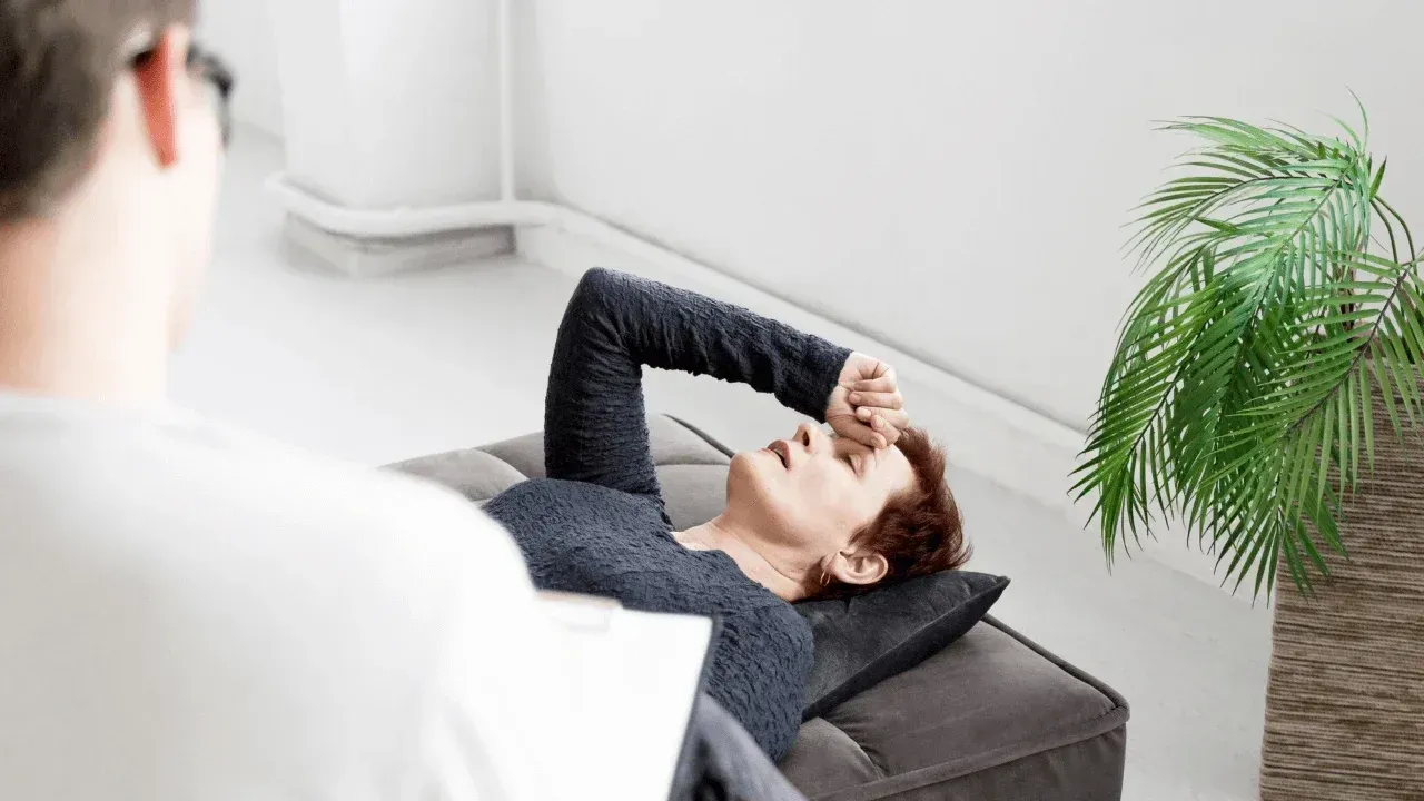 Un investigador con bata de laboratorio y gafas observa a dos ratones blancos en un recinto de cristal.