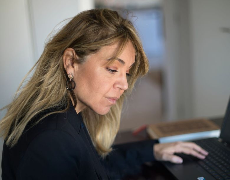 Una mujer está sentada en un escritorio utilizando una computadora portátil.