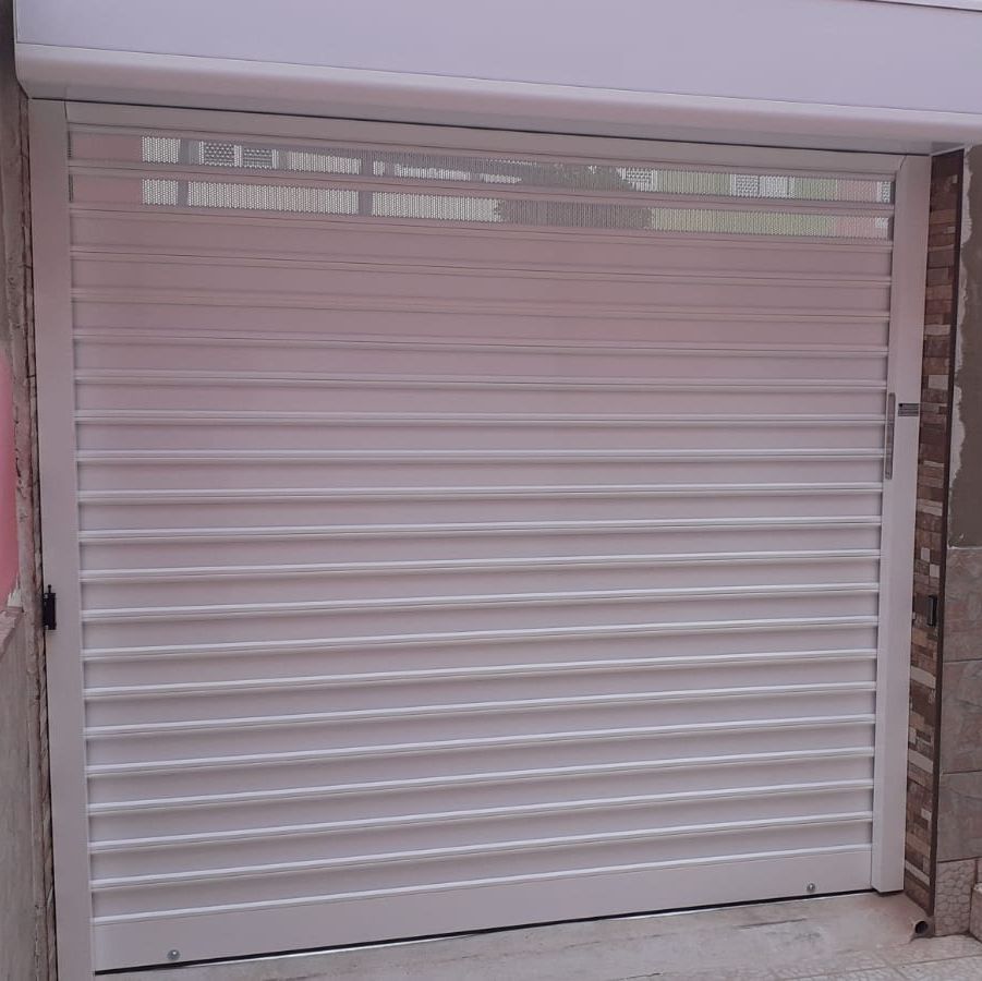 Una puerta de garaje blanca está situada en el costado de un edificio. con una puerta enrollable