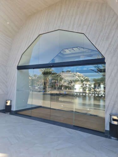 Una gran puerta de cristal con el reflejo de un edificio en ella.